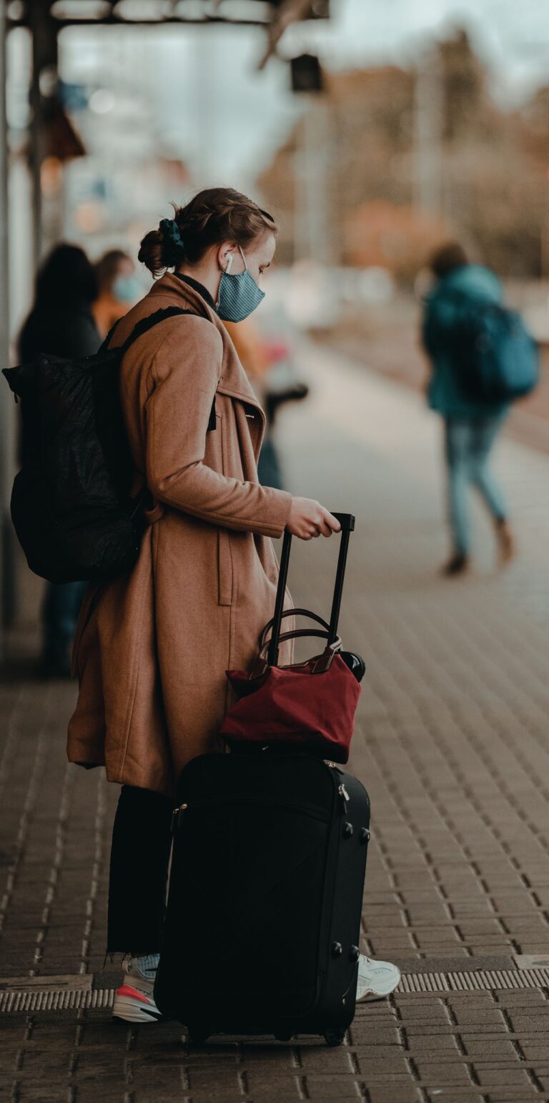 Trabalhadora com mala esperando transporte após mudança de cidade a trabalho