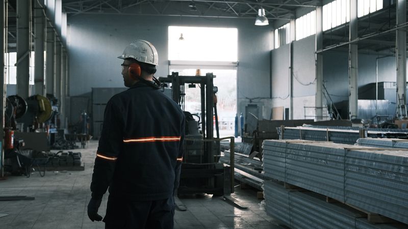 Trabalhador de capacete caminhando dentro de um galpão industrial