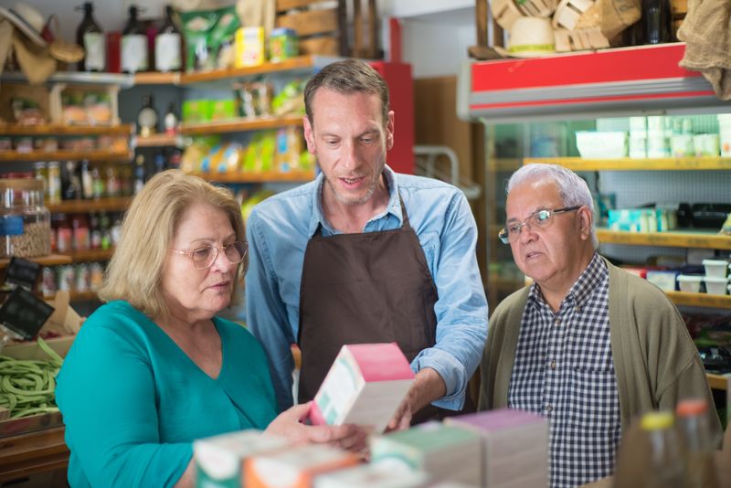 Vendedor atendendo dois clientes em uma loja de conveniência