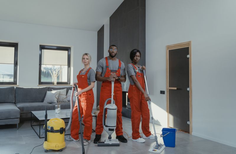 Equipe de profissionais de limpeza domiciliar uniformizados em uma sala de estar