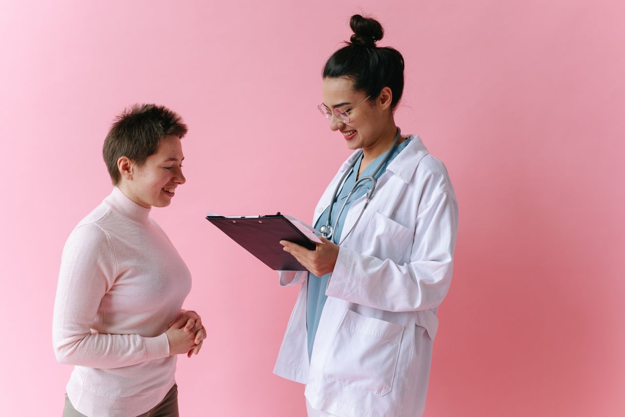 Médica conversando com paciente e anotando informações em prancheta