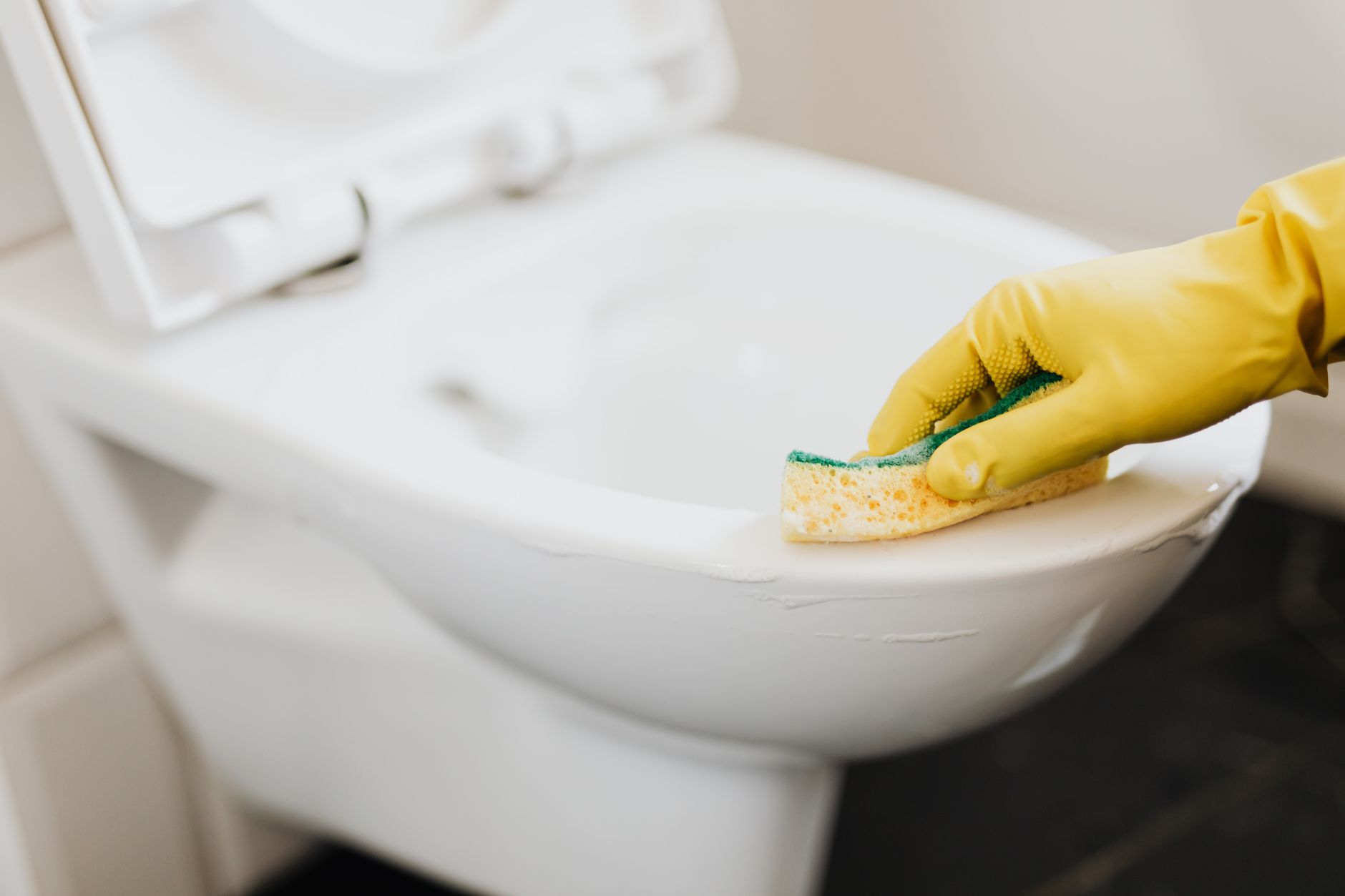 Profissional de limpeza higienizando banheiro de uso coletivo