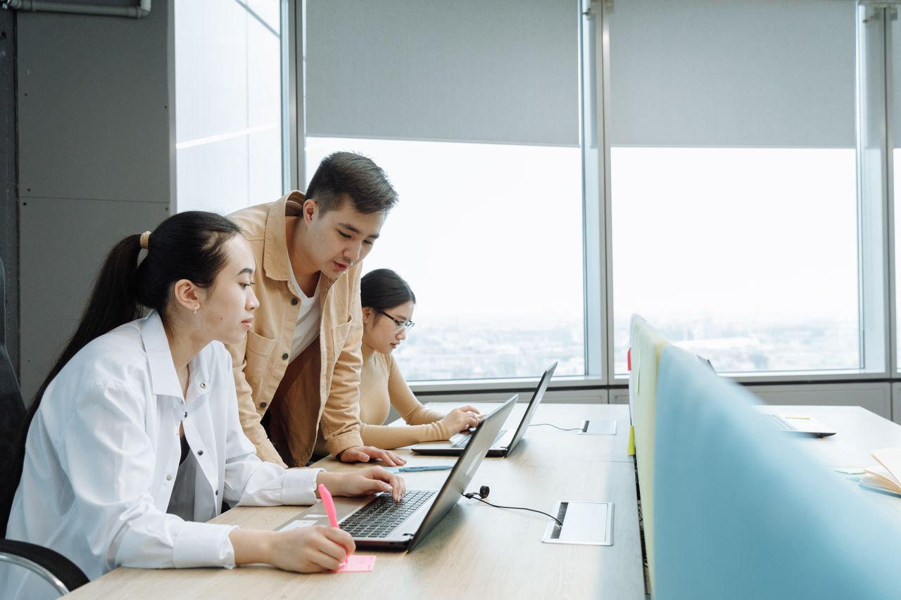 Trabalhadores conversando em frente ao computador no escritório