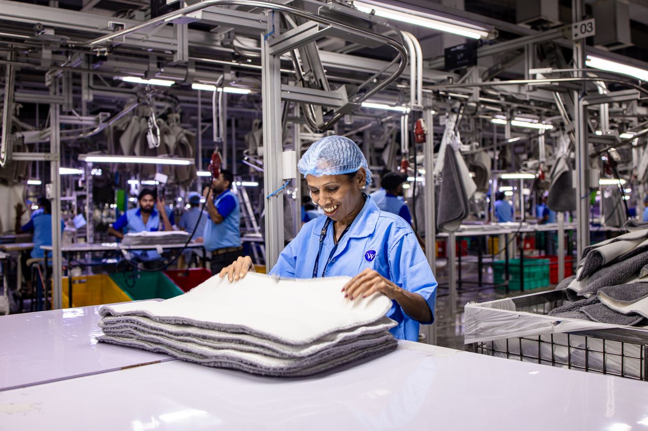Trabalhadora sorrindo em ambiente de fábrica, representando o cotidiano de quem tem direitos protegidos no trabalho