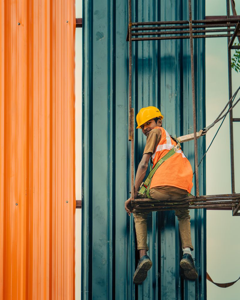 Trabalhador em obra realizando serviço com capacete e colete de segurança