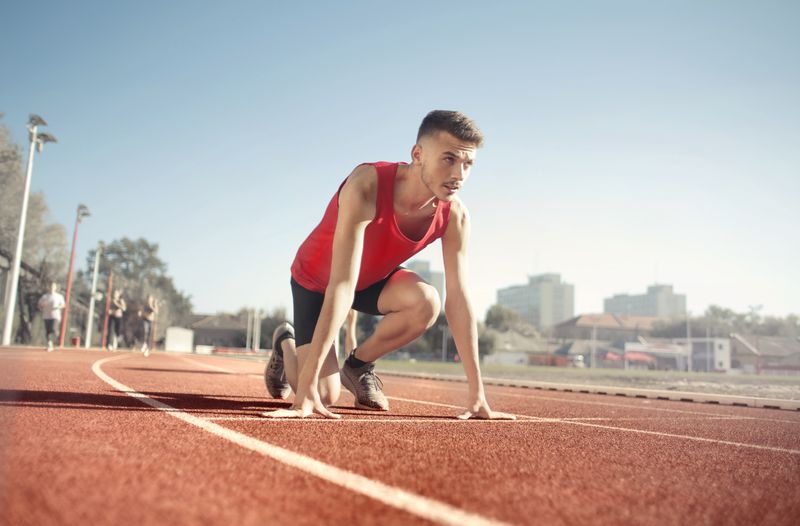 Atleta em posição de largada representando atividade física de alta intensidade e risco de lesão