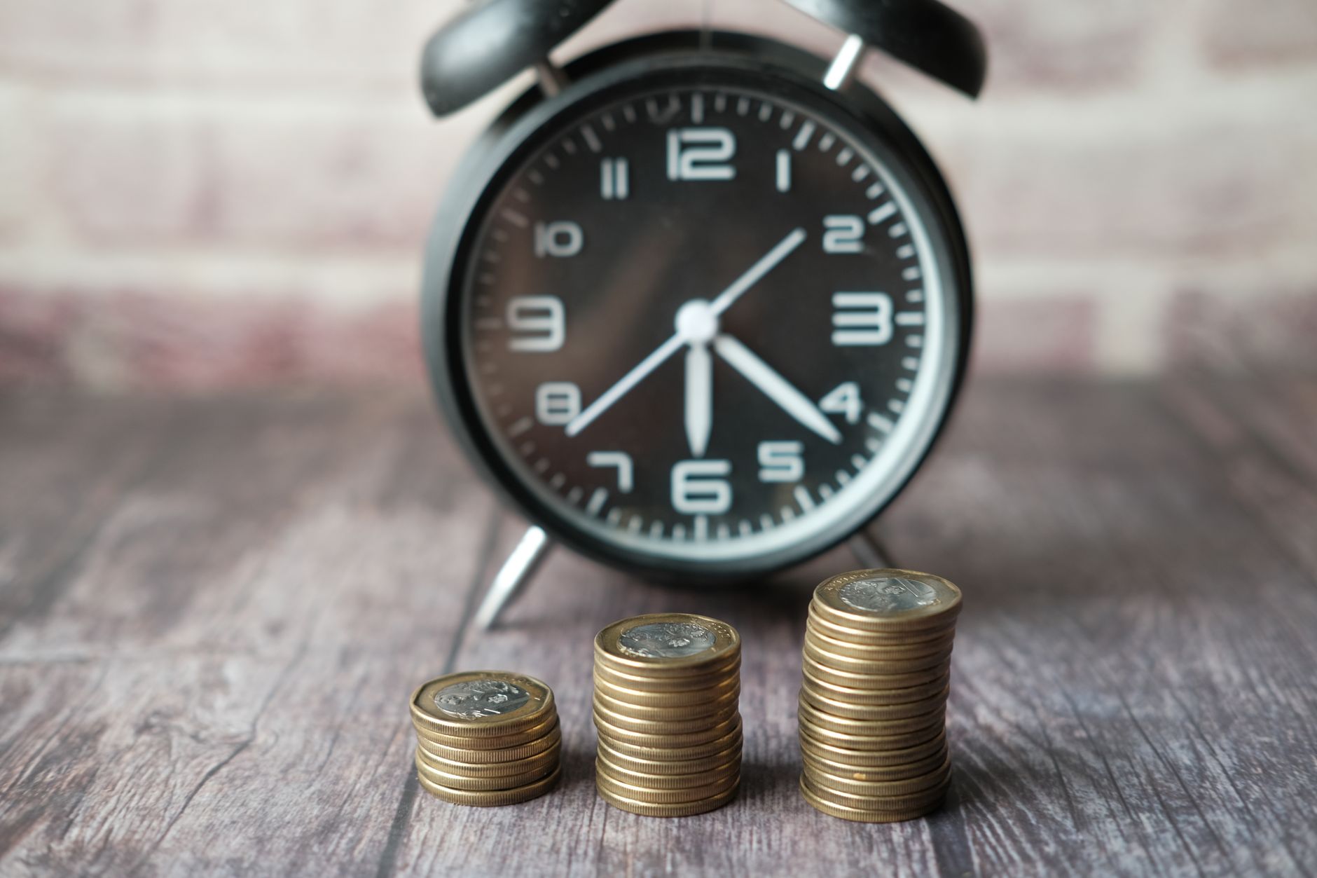 Relógio ao lado de dinheiro simbolizando o tempo e a correção monetária de dívidas trabalhistas