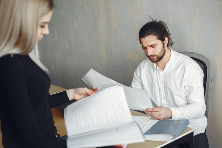 Trabalhador analisando documentos de demissão com colega no escritório