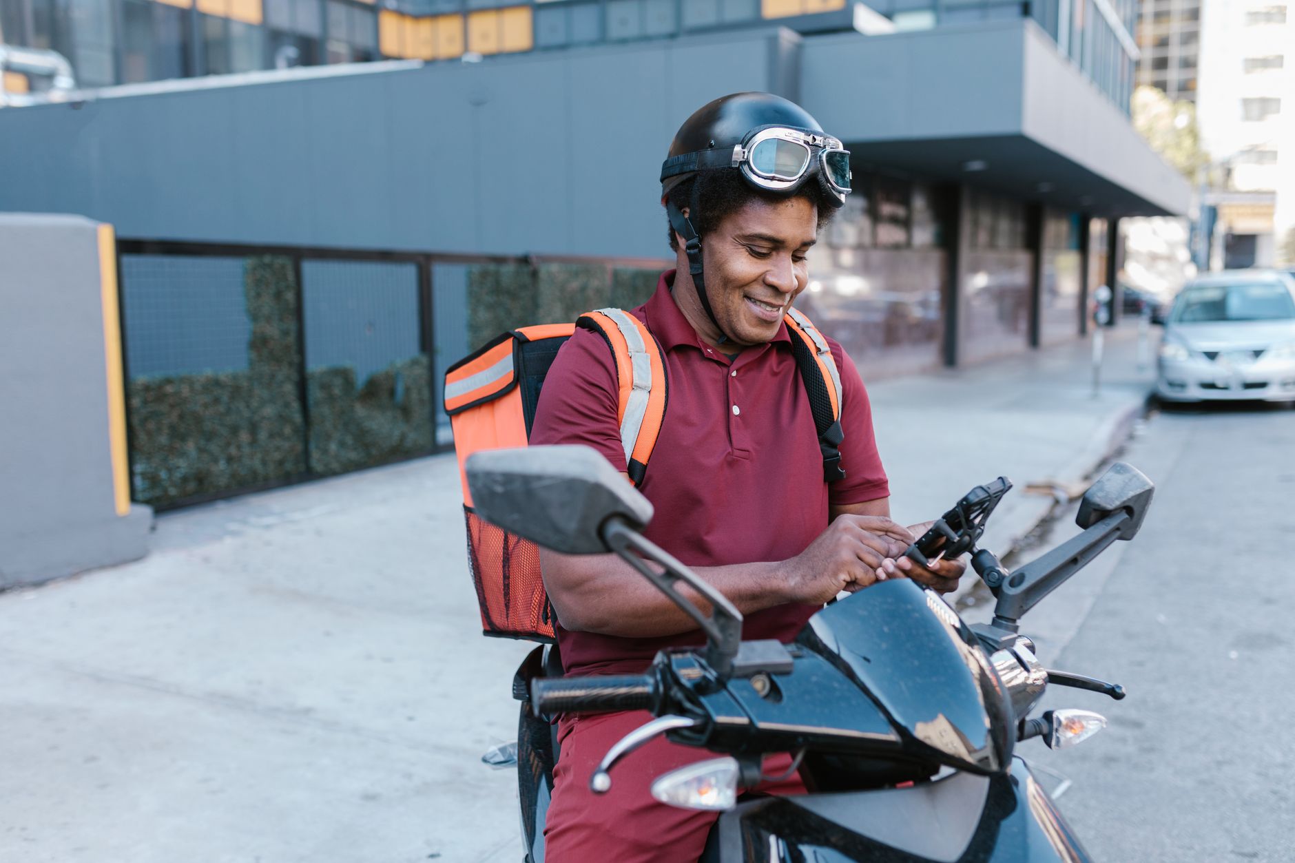 Entregador em moto consultando aplicativo de rastreamento no celular
