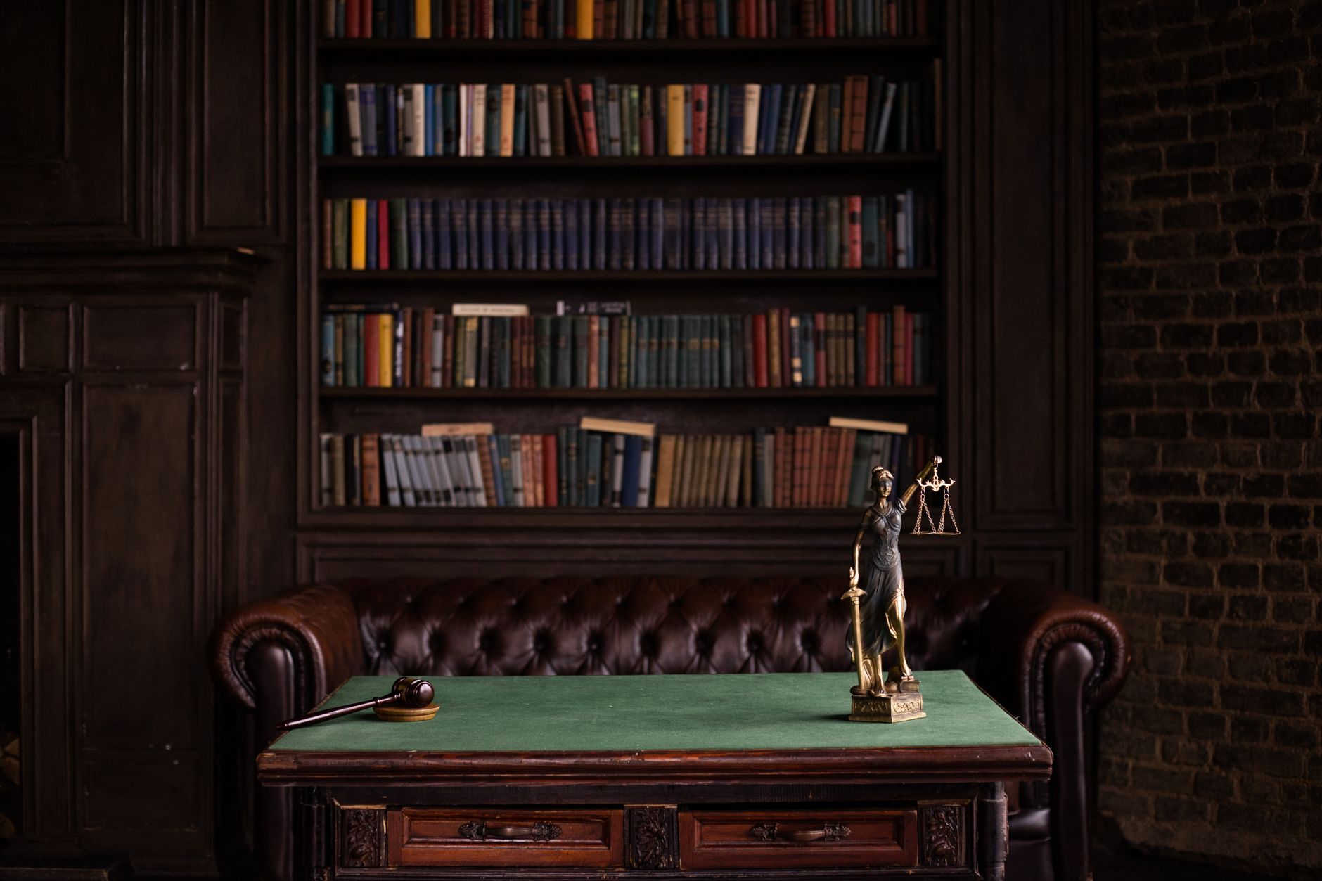 Livros de direito, martelo de juiz e estátua da Justiça sobre mesa