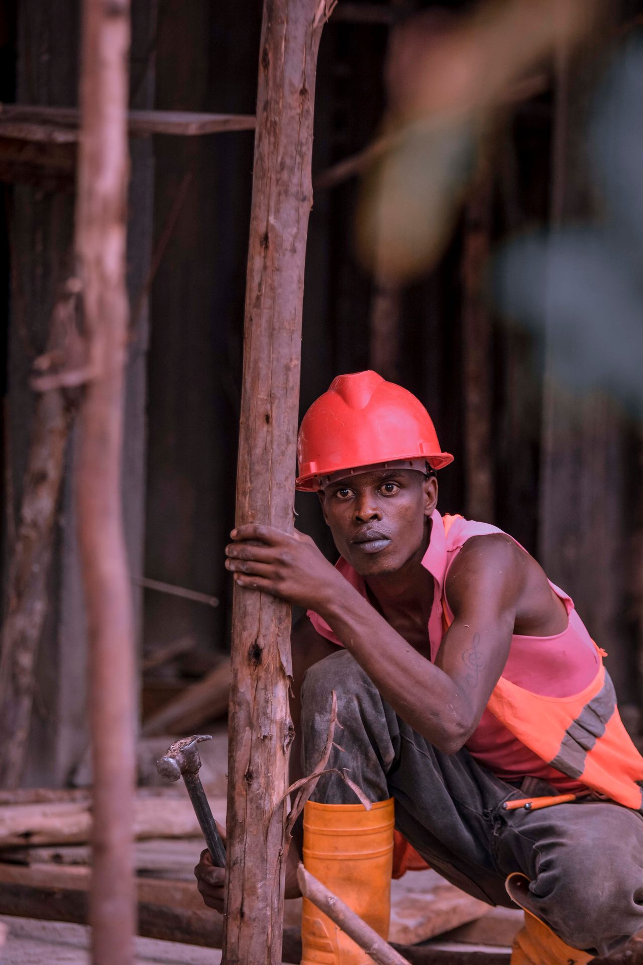 Trabalhador agachado em canteiro de obras segurando ferramenta