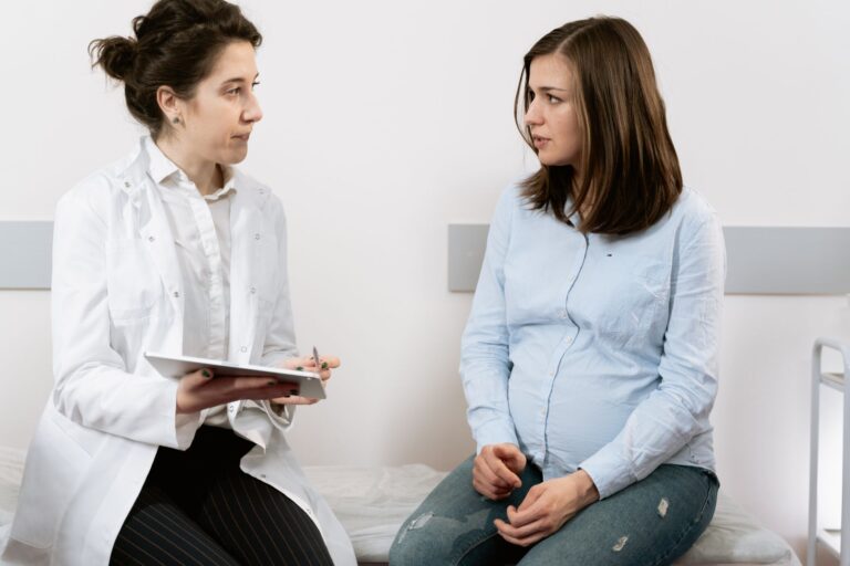 Gestante em consulta médica com profissional de saúde em clínica