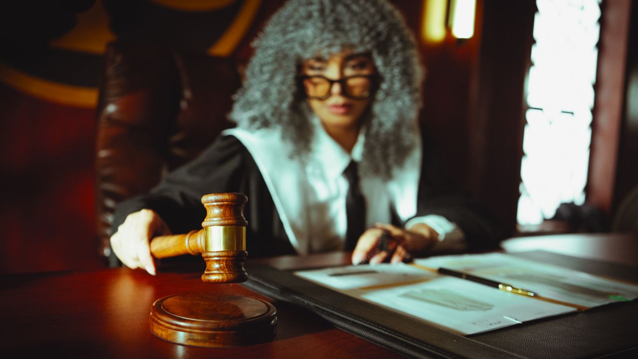 Juíza com martelo analisando documentos em audiência trabalhista