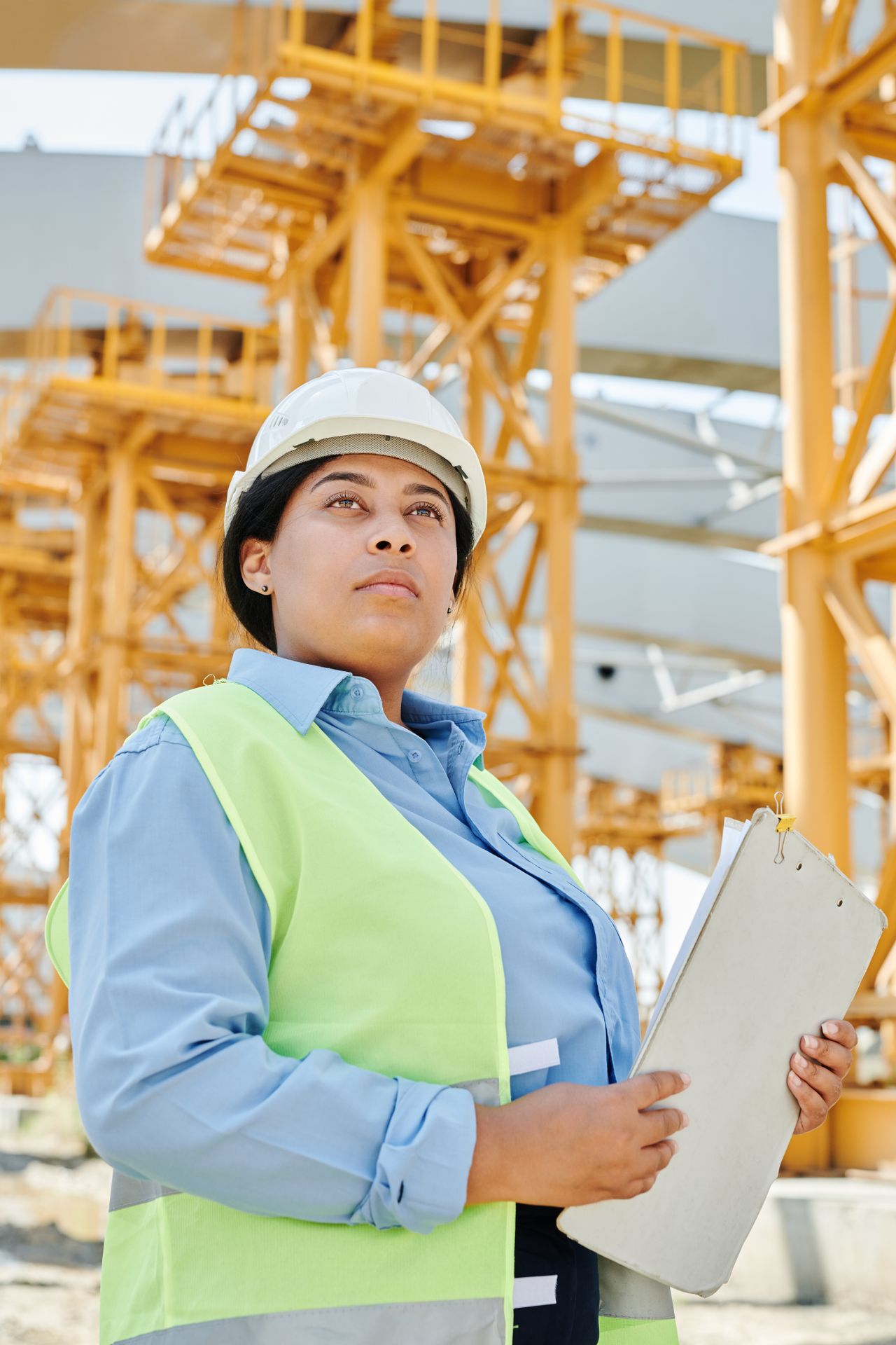 Trabalhadora usando capacete e colete de segurança em ambiente industrial