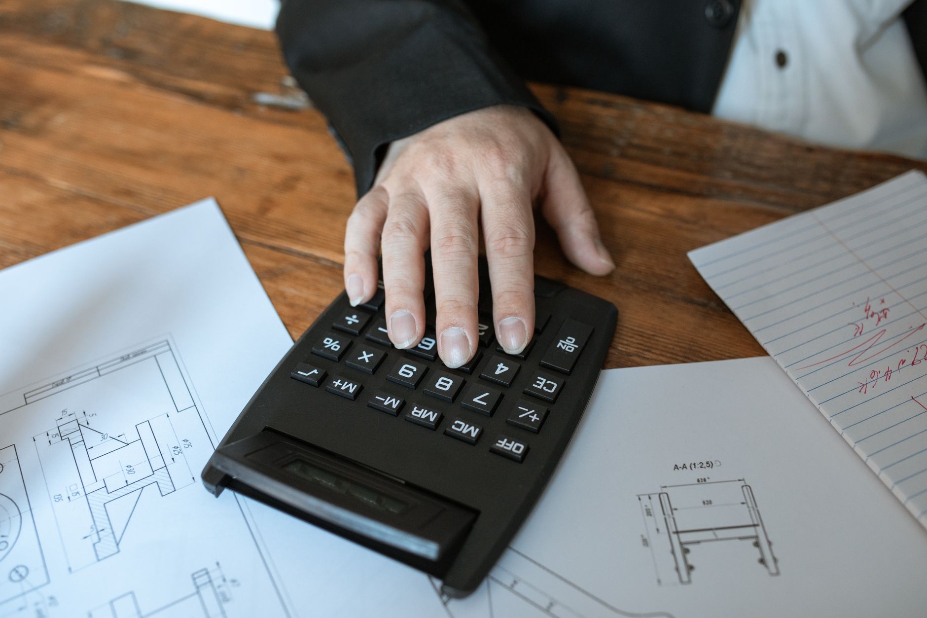 Mão usando calculadora para fazer o cálculo do 13º salário