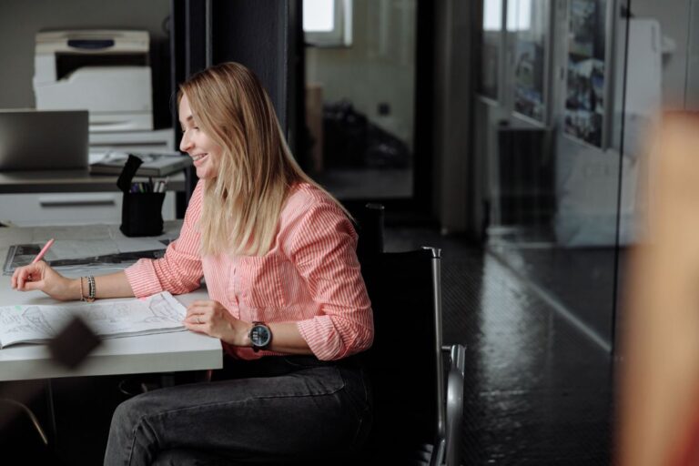 Mulher sorridente em ambiente de escritório, representando o retorno de trabalhador ao emprego