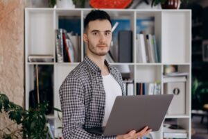 Homem segurando notebook em ambiente de escritório, ilustrando devolução de equipamento e desconto salarial indevido