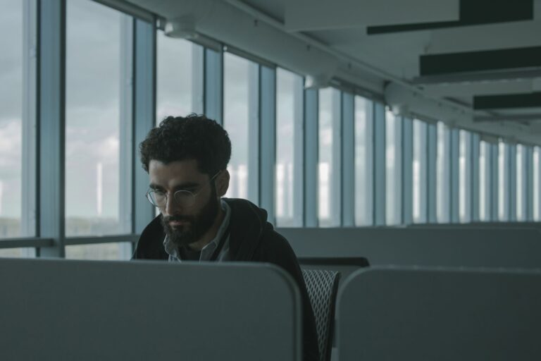 Trabalhador sentado sozinho em cubiculo de escritorio, isolado dos colegas