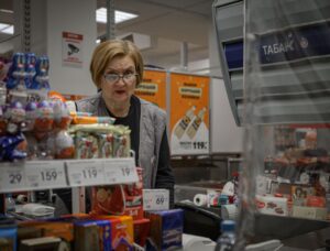 Operadora de caixa atendendo cliente em supermercado, ilustrando trabalho no comércio aos domingos