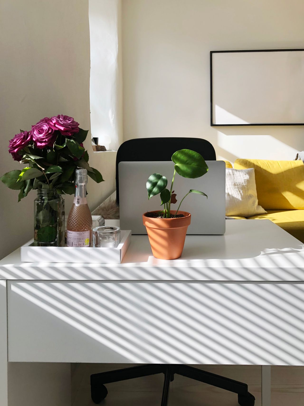 Mesa de home office organizada com notebook, plantas e itens de trabalho remoto