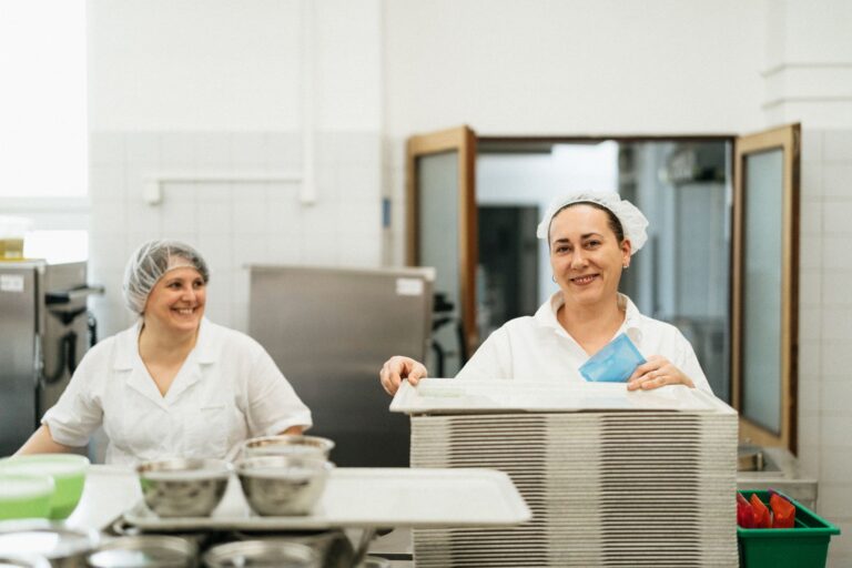 Duas funcionarias trabalhando em uma cozinha de refeitorio