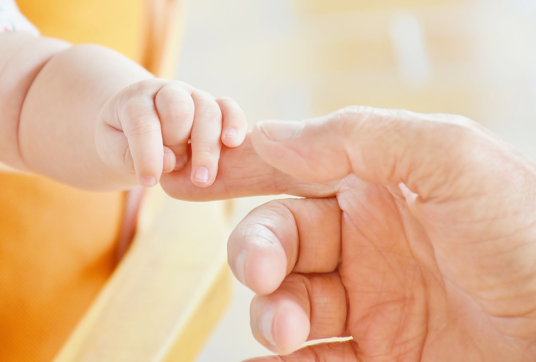 Mão de bebê recém-nascido segurando o dedo do pai