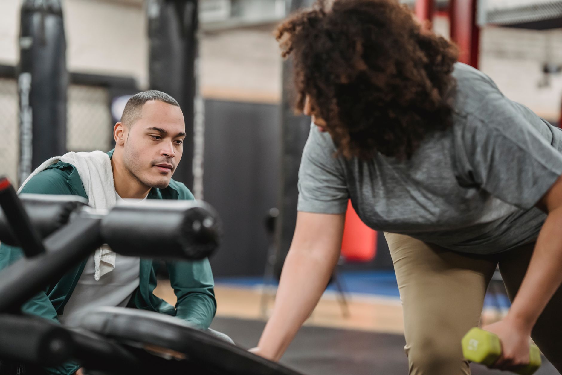 Personal trainer acompanhando aluno em exercício com peso na academia