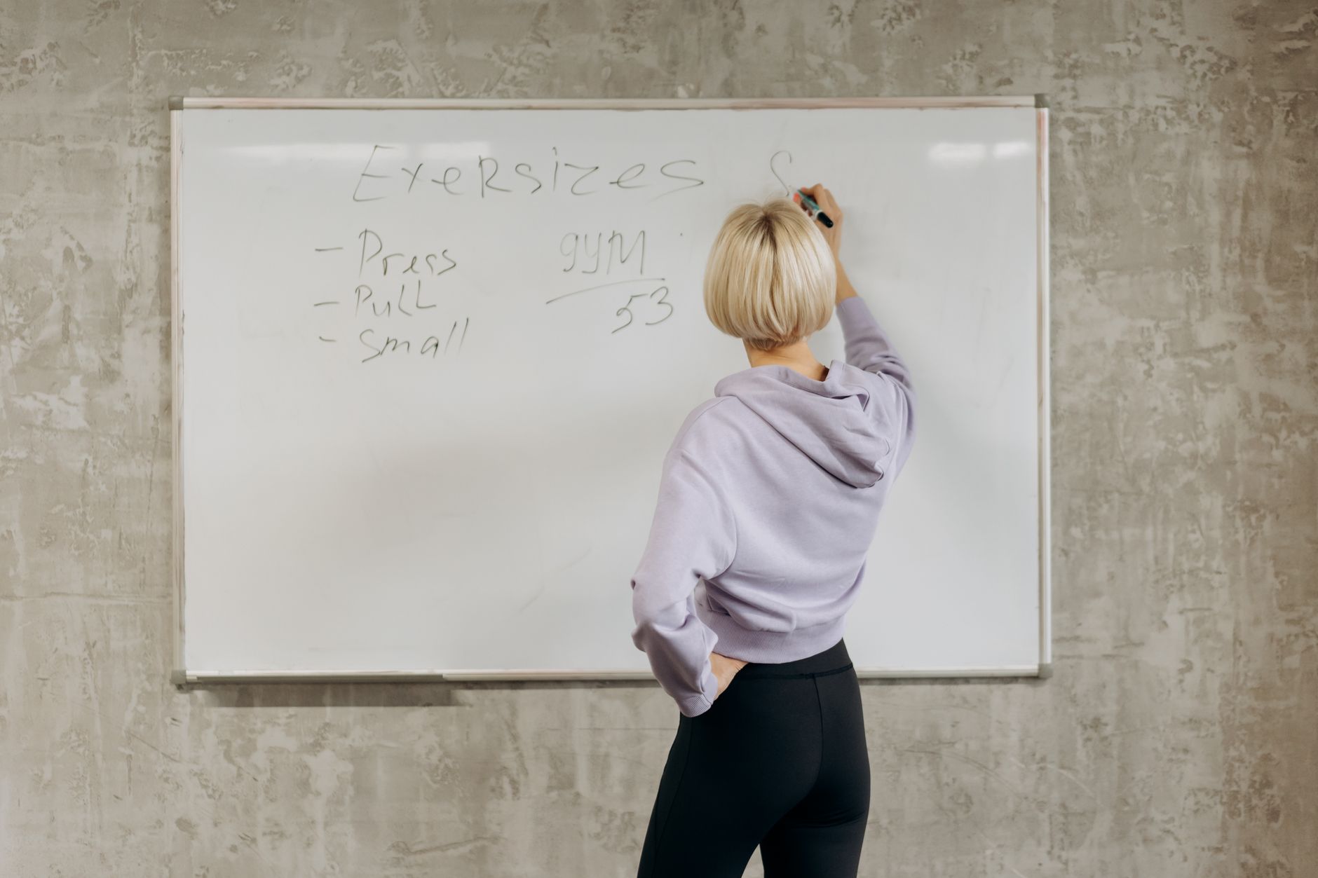 Personal trainer planejando treino em quadro na academia