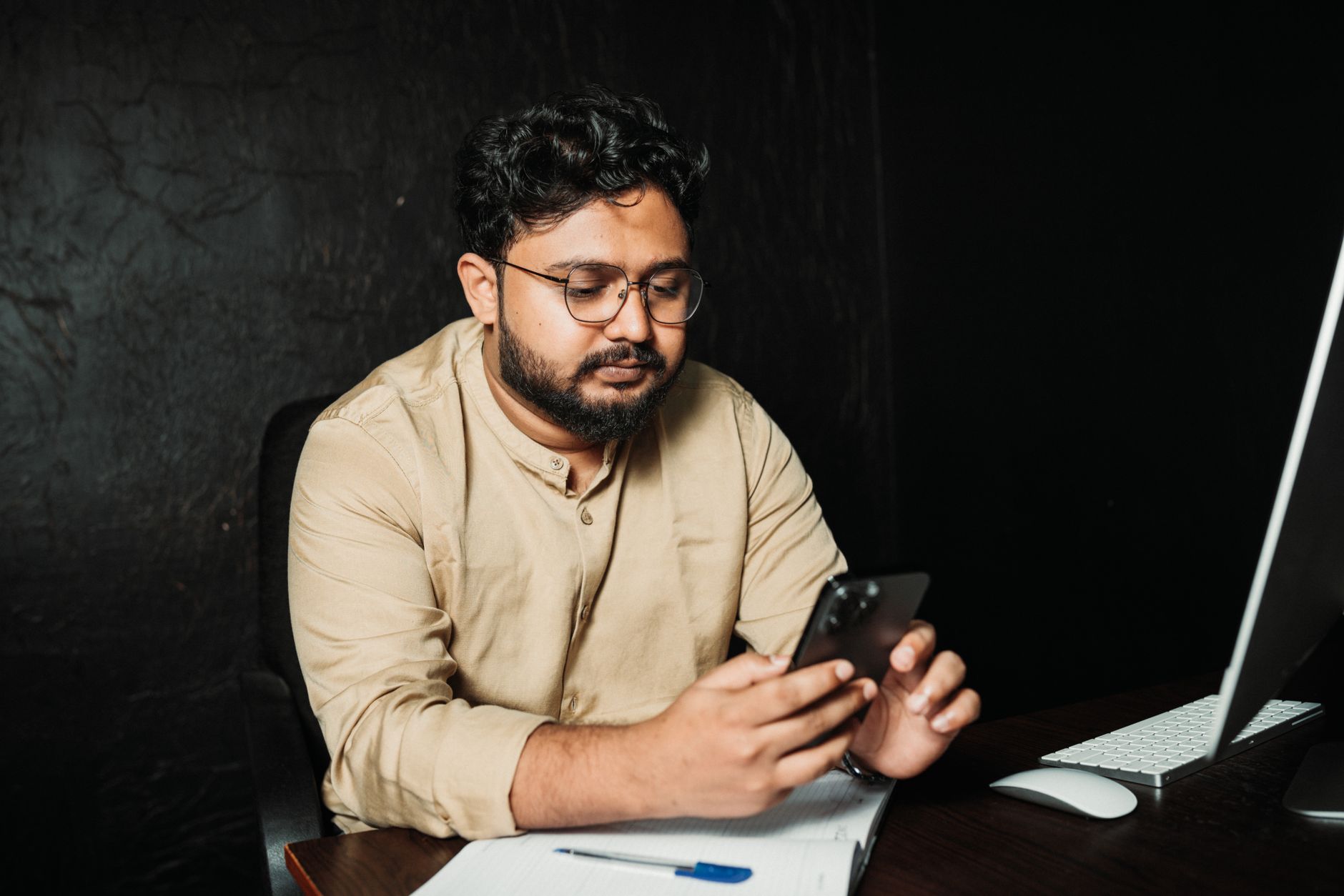 Trabalhador usa o celular na mesa do escritório, momento em que pode registrar uma prova para processo trabalhista