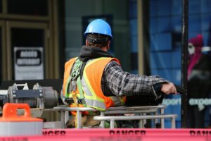 Trabalhador da construcao civil com casco e colete de seguranca em canteiro de obras