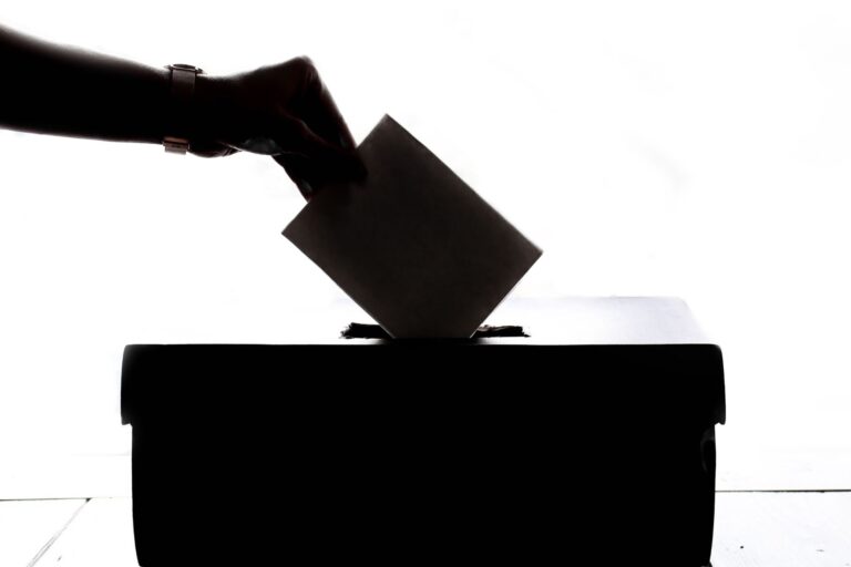 Mão depositando voto em urna eleitoral