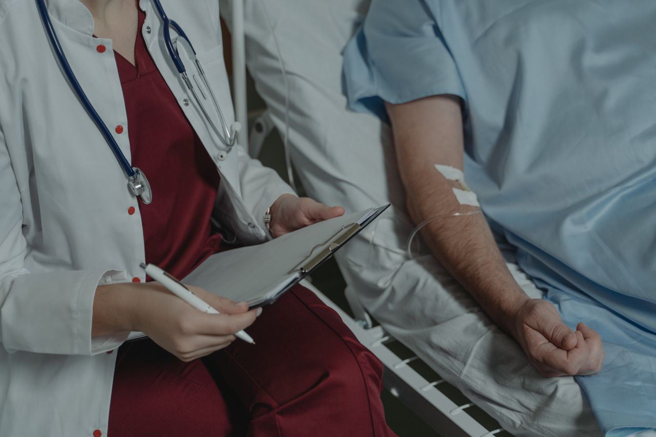 Médica registrando informações no prontuário ao lado de paciente em atendimento