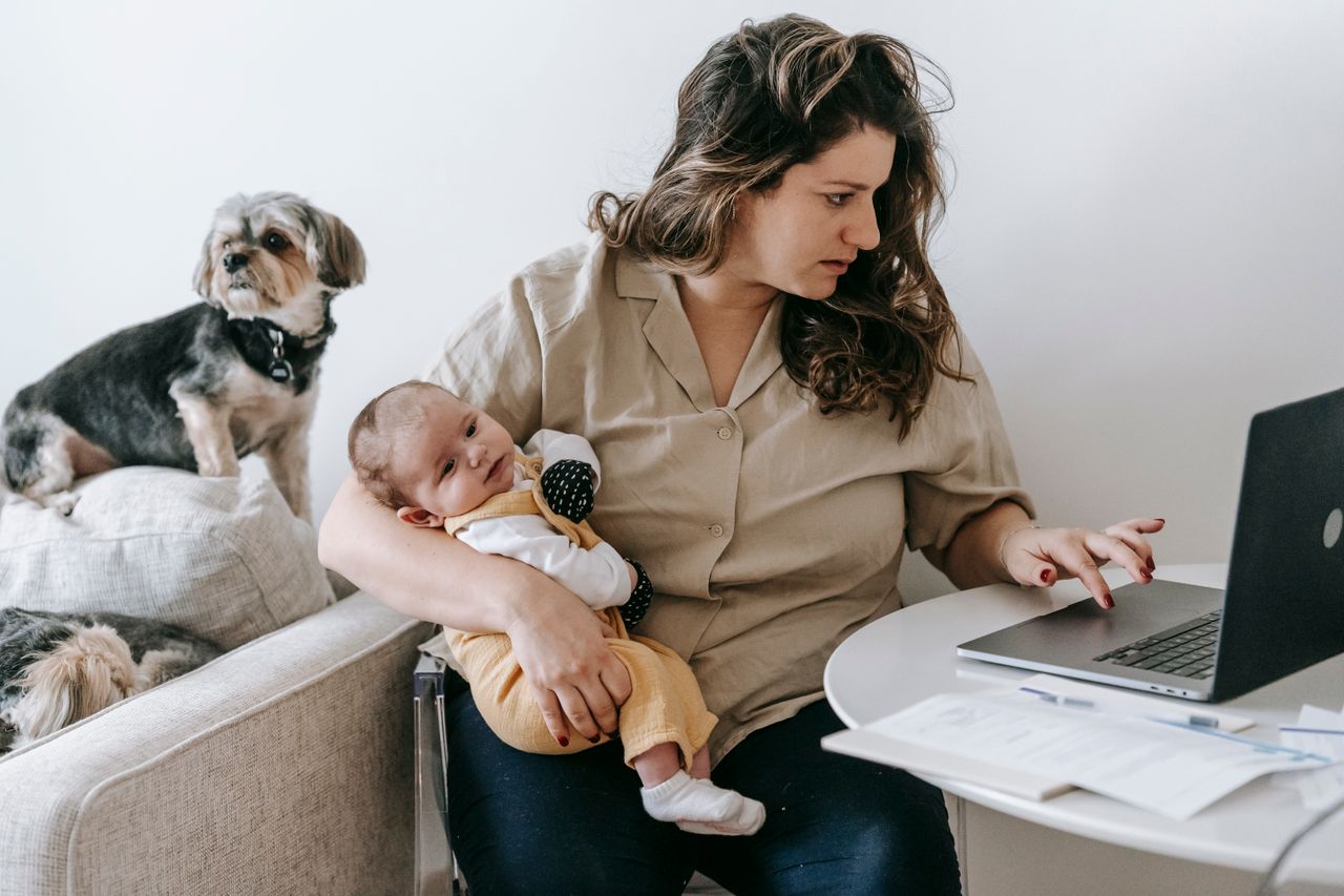 Mãe trabalhando no notebook com o bebê no colo