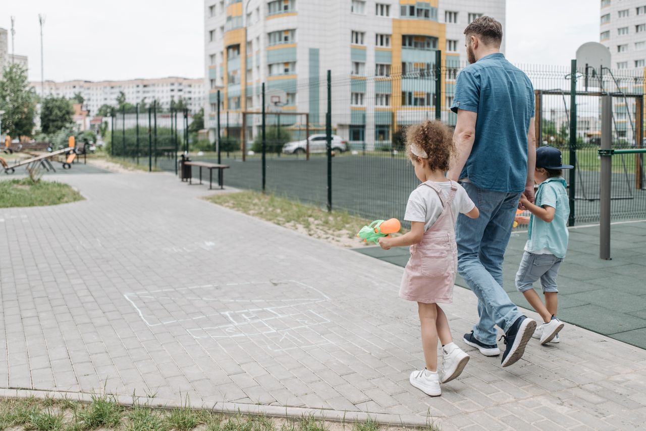 Pai caminhando com os filhos pequenos de mãos dadas