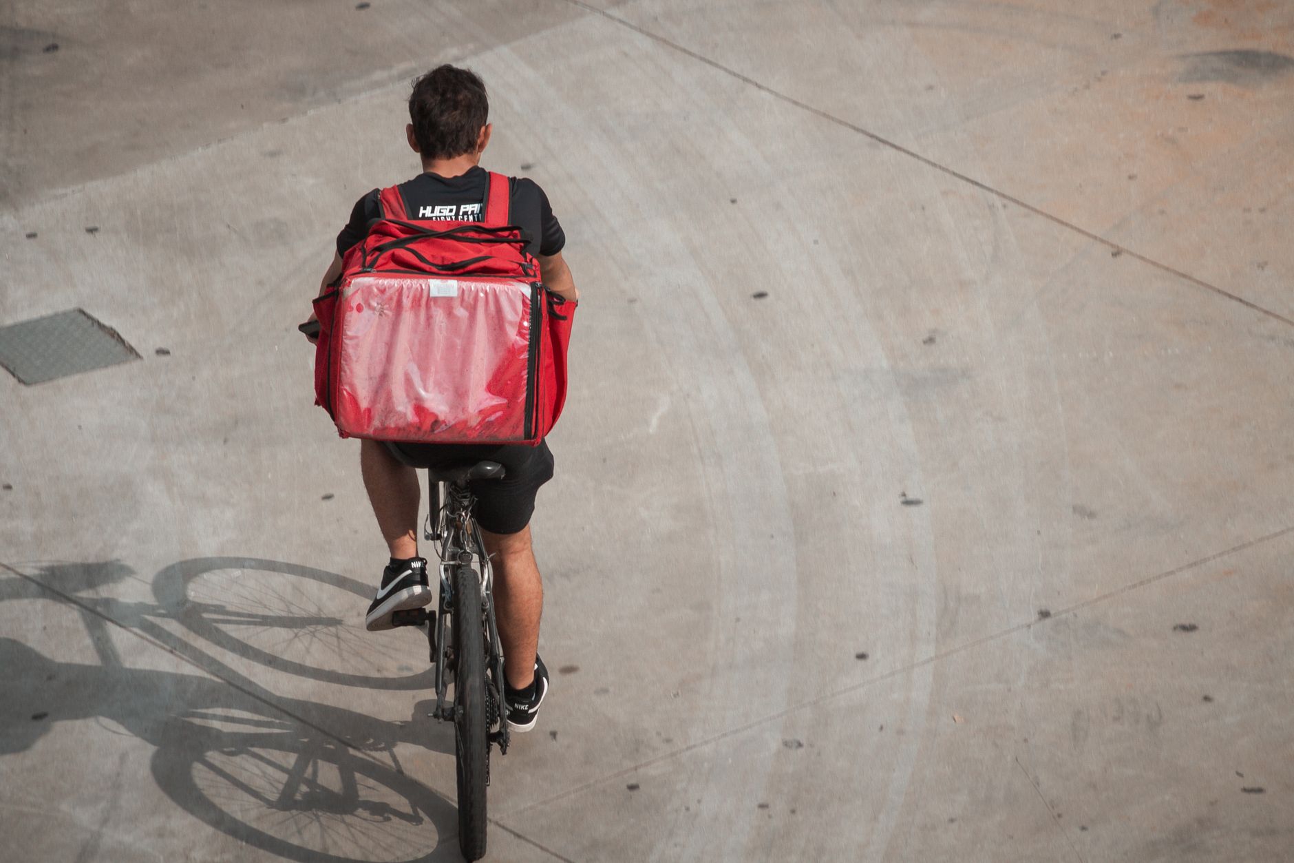 Entregador com mochila fazendo entrega em bicicleta