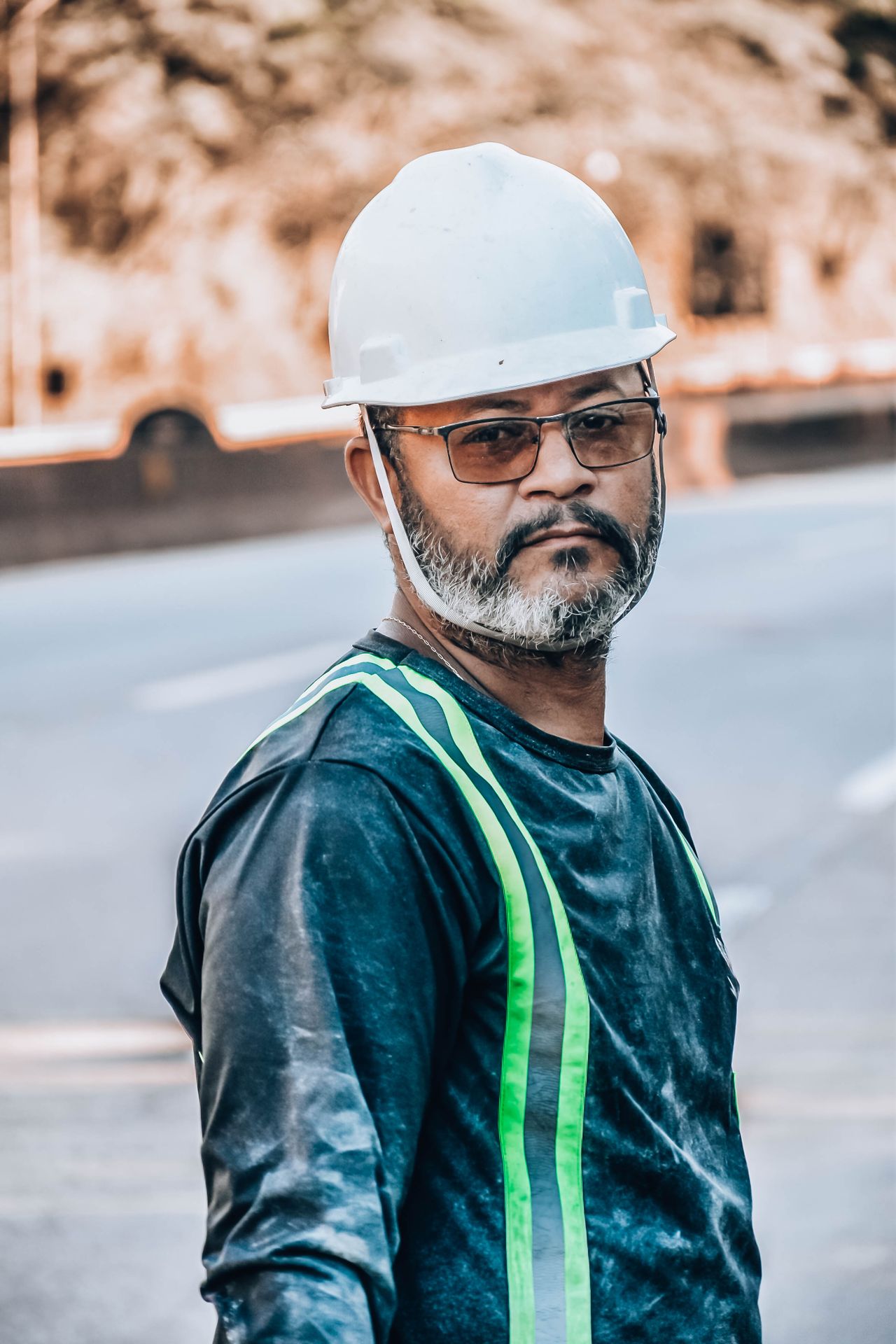 Trabalhador de capacete e colete em ambiente industrial olhando para o lado