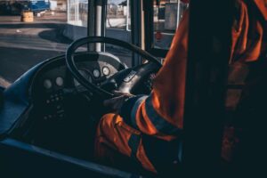 Motorista de ônibus ao volante, visto de dentro do veículo