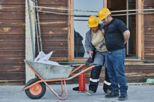 Trabalhadores de capacete auxiliando colega ferido em obra