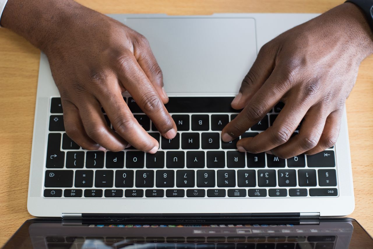 Trabalhador digitando em notebook na mesa de escritório